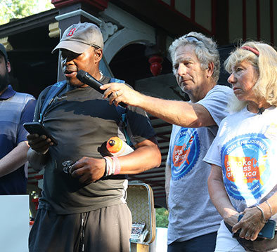 A man being assisted while he gives a speech to a crowd